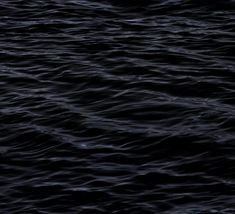 black and white photograph of the ocean with dark water in the foreground, looking like waves