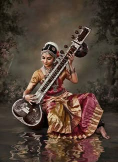 a woman sitting in the water holding an instrument