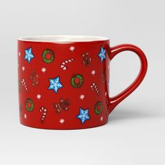 a red coffee mug with christmas cookies and candy canes printed on the side, sitting in front of a white background