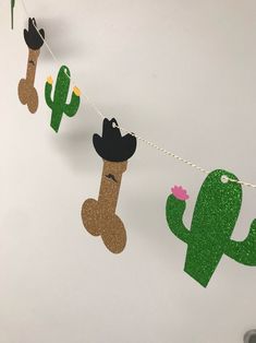 cactus and cowboy hats are hanging from a string on the wall in front of a white wall