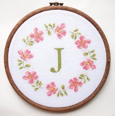 a cross stitch pattern with the letter j in it's center surrounded by pink flowers