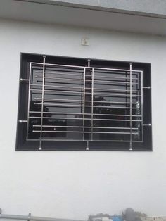 a window with metal bars on the side of it in front of a white wall