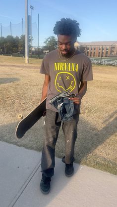 a young man holding a skateboard on the sidewalk