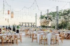 an outdoor dining area with tables and chairs set up for a wedding reception at the beach