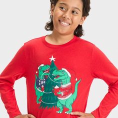 Your child will love showing their excitement for the festive season in this Long-Sleeve Christmas Dino Graphic T-Shirt from Cat & Jack™. Crafted from cotton-recycled polyester blend fabric, this long-sleeve T-shirt brings cozy comfort to their day, while the below-waist length gives them the option of wearing it tucked in or untucked. Designed in a red hue, this crewneck tee features a graphic showing two dinosaurs around an embellished Christmas tree wearing Santa hats and festive sweaters whi Festive Sweaters, Santa Hats, How To Show Love, Boys Long Sleeve, Cat & Jack, Comforters Cozy, Waist Length, Festive Season, Santa Hat