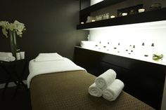 towels are folded up on the bed in a spa room with white flowers and candles