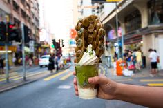 a person holding up an ice cream sundae in the middle of a city street