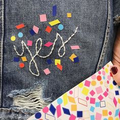 a baby laying on top of a colorful blanket next to a pair of blue jeans