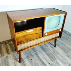 an old fashioned television sitting on top of a wooden cabinet in a room with tile flooring