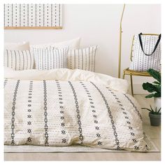 an image of a bed with white sheets and black trims on it, next to a plant