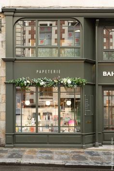 a store front with many windows and flowers in the window