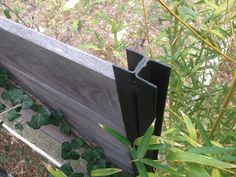 a close up of a wooden fence with green plants growing around it and an opening in the side