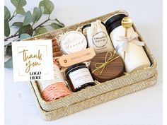 a gift box with soaps, candles and other personal care items in it next to a plant