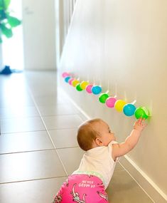 a baby is playing with some balloons on the wall