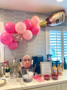 a kitchen counter topped with lots of pink and white balloons next to a bottle of champagne