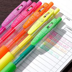 four different colored pens sitting on top of an open notebook with the same pen in it