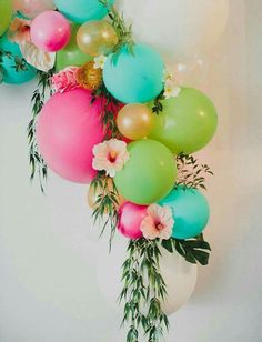 colorful balloons and greenery are arranged in the shape of a garland on a white wall