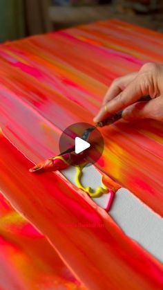 someone is using scissors to paint an orange and red table