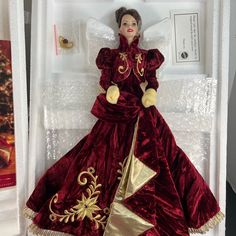 a doll in a red dress with gold trim