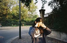 a woman standing on the side of a road holding her hands to her face