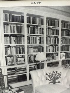 an old black and white photo of a living room with bookshelves full of books