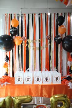 an orange and black birthday party with balloons, streamers, tassels and decorations