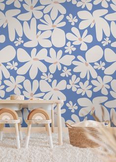 two children's wooden chairs sitting in front of a blue wall with white flowers on it