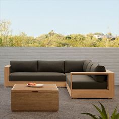 a couch and coffee table in front of a white brick wall with trees behind it