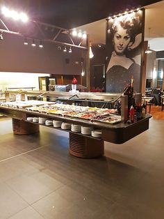 a buffet table with many plates and cups on it in a large room filled with people