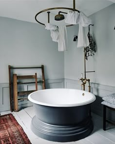 a white bath tub sitting in a bathroom next to a wooden table and chair on top of a rug