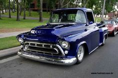 an old blue truck is parked on the side of the road next to other cars