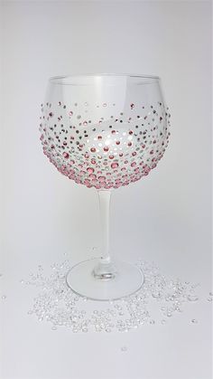 a wine glass filled with lots of confetti on top of a white table