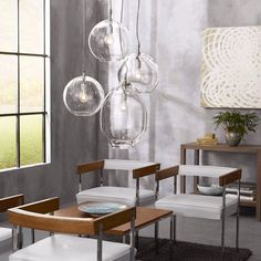 a dining room table with four chairs and hanging glass globes on the wall above it