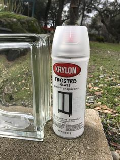 a bottle of krylon frosted paste next to a glass block on the ground