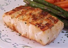 a white plate topped with fish and asparagus