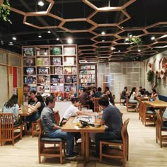 people sitting at tables in a restaurant with bookshelves on the wall behind them