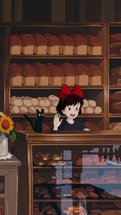 a woman standing in front of a bakery counter next to a black cat and sunflower