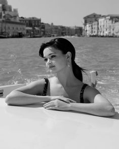 a woman sitting on the back of a boat in front of some buildings and water