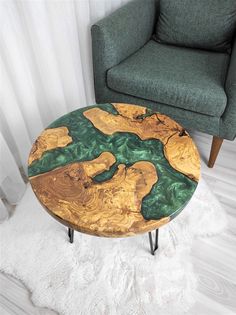 a coffee table with green and yellow paint on it in front of a gray chair