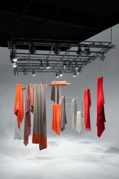 several scarves hanging from the ceiling in an empty room with lights above them,