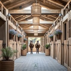 two horses are standing in the middle of an enclosed area with potted plants on either side