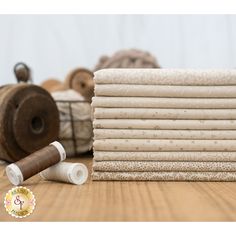 a stack of white towels sitting on top of a wooden table next to twine spools