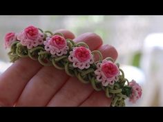 a hand is holding some pink and green flowers