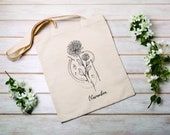 a tote bag sitting on top of a wooden table next to some white flowers