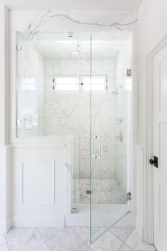 a walk in shower sitting next to a white door and window on top of a wall