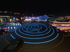 an aerial view of a city at night with lights on the ground and buildings in the background