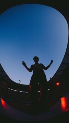 the silhouette of a person standing in front of a large circular object with its arms outstretched