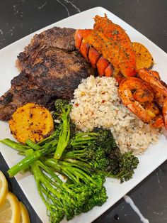 a white plate topped with meat and veggies next to lemon wedged potatoes