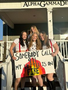 three girls are holding a sign that says somebody call my fire on the front porch