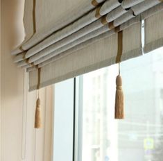 a window with some curtains hanging from it's side and tassels on the top